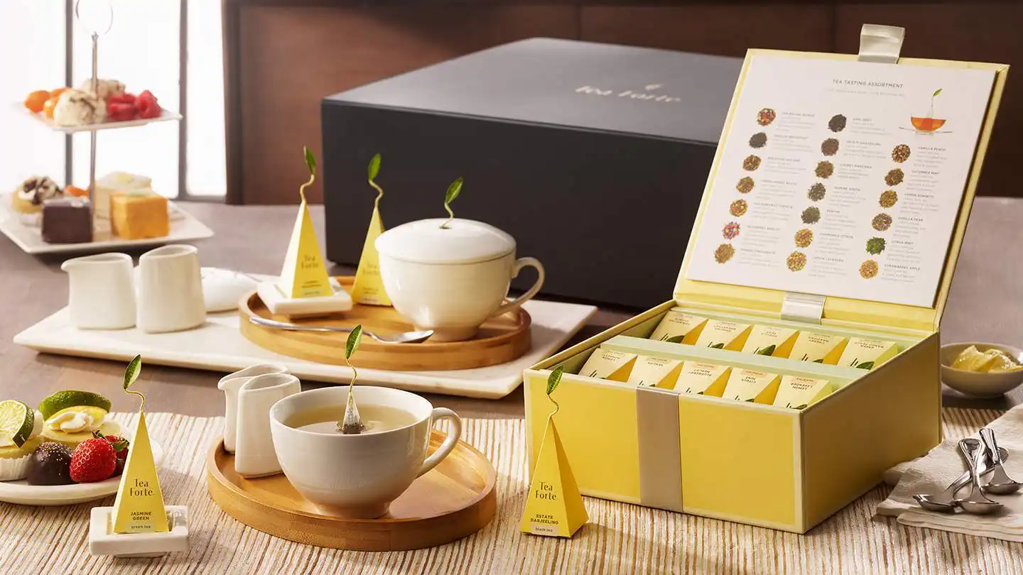 Set cadou Tea Forté Ultimate Tea Gift Set deschis pe masă, cu piramide de ceai, ceainic și cești